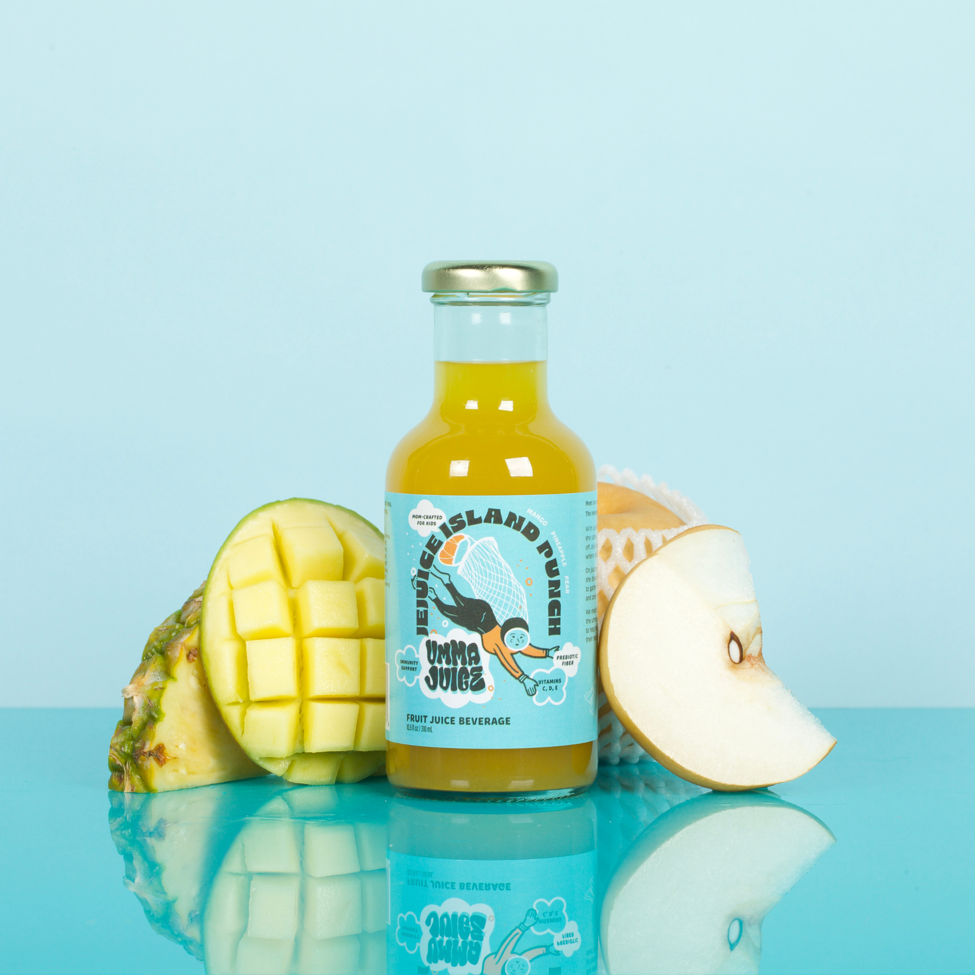 Bottle of juice with a blue label surrounded by pineapple, mango, and pear on a reflective surface with a light blue background