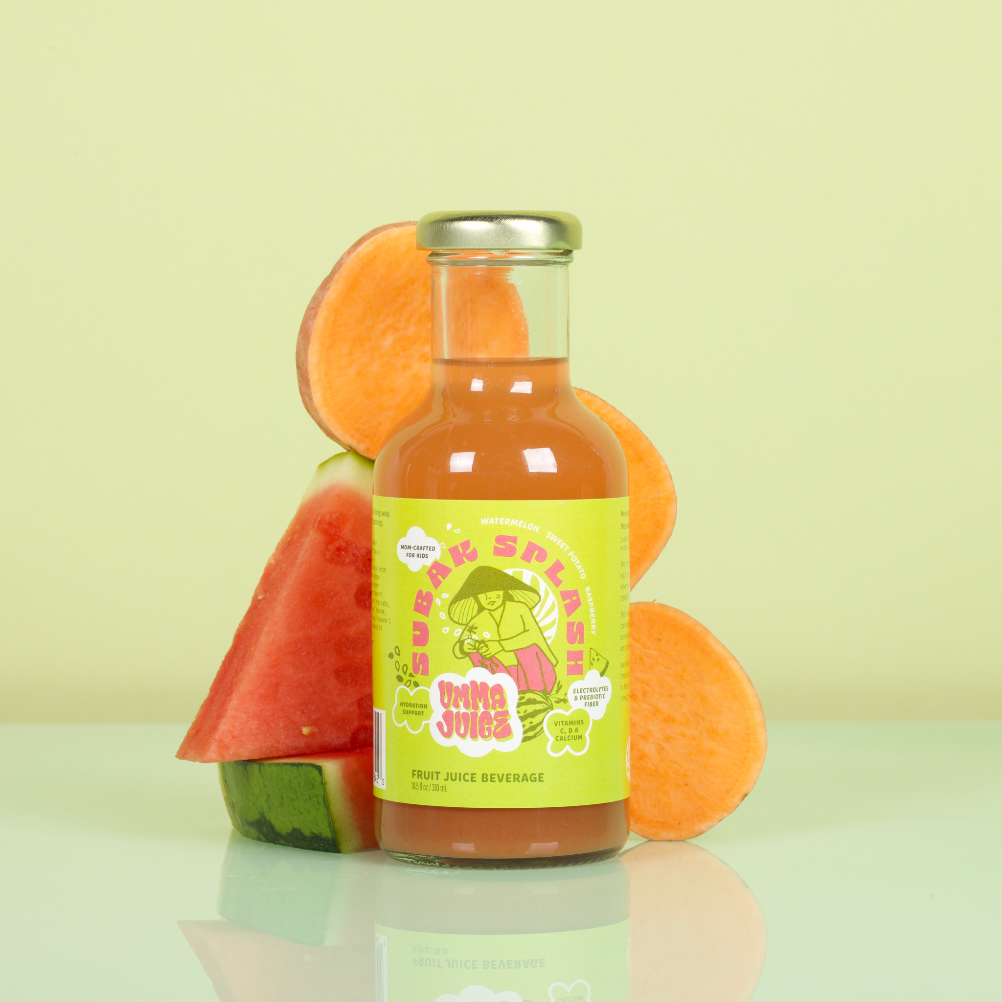 Bottle of juice with a colorful label surrounded by watermelon slices and sweet potato on a light green background
